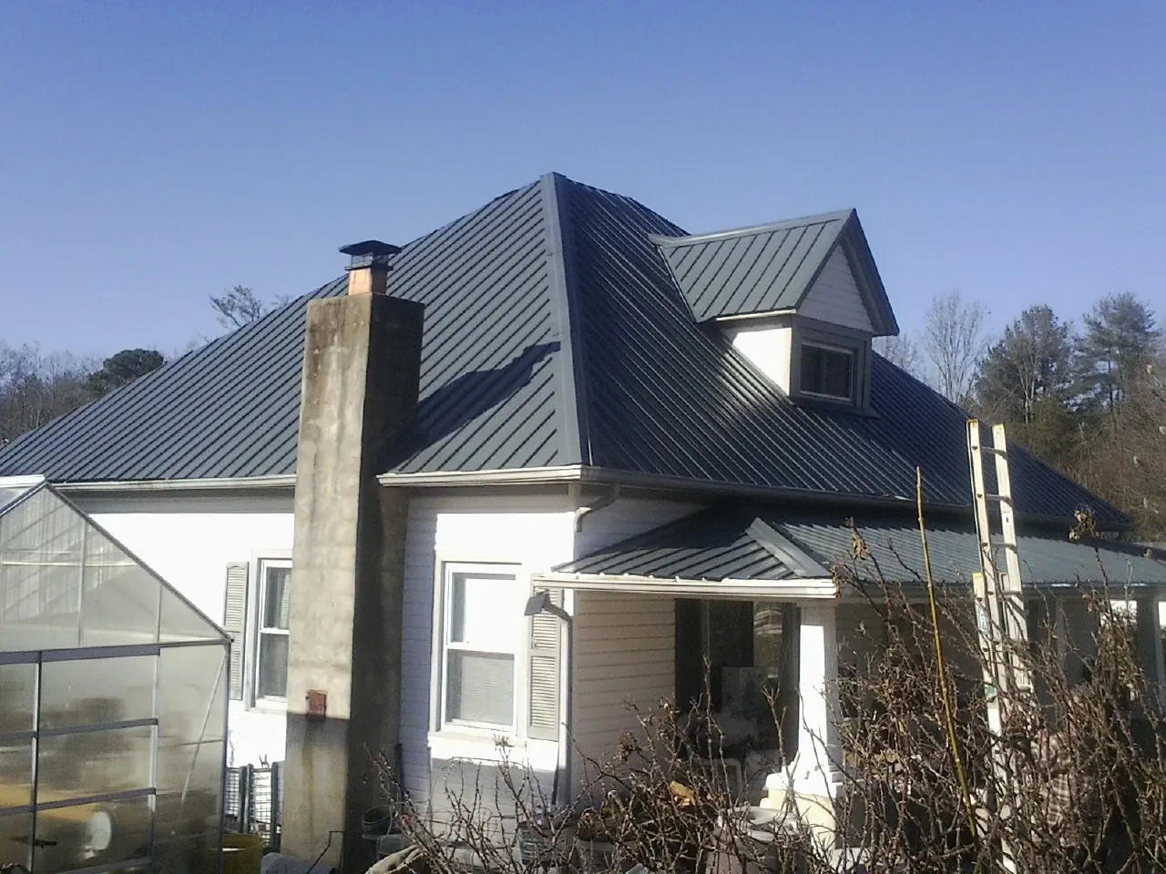 Dark blue standing seam metal roof on a white farmhouse with dormer — Slate & Tile Roof Repair by Roofing Brothers in Texarkana