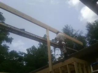 Carpenter setting a ridge beam over a new addition frame — Ice Dam Removal by Roofing Brothers in Texarkana