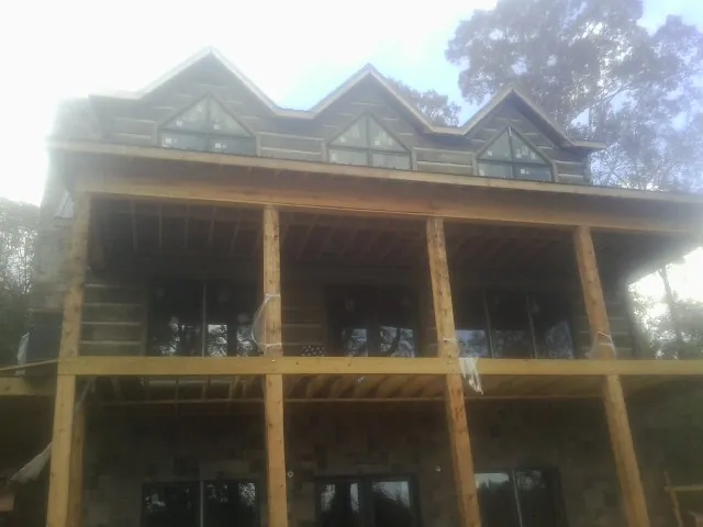 Dormers and porch framing on a large log home under construction — Roof Coating work by our crew in Texarkana