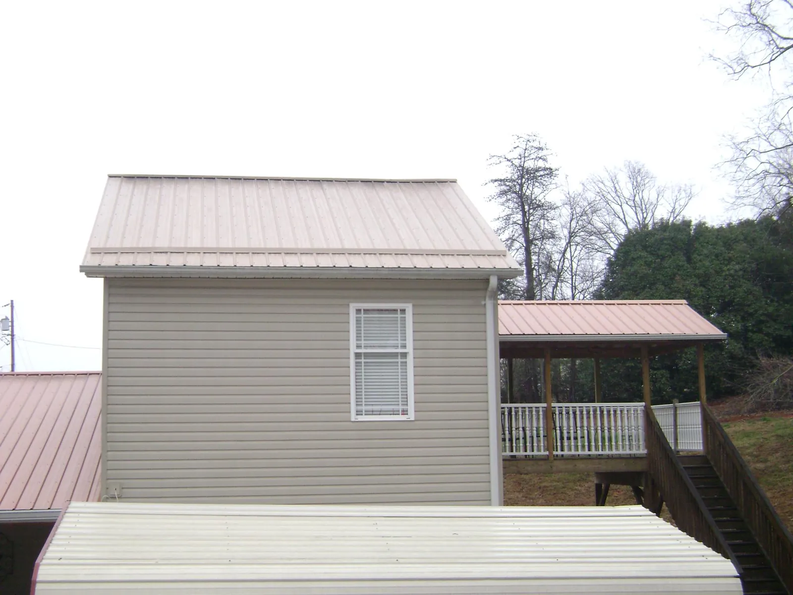 Tan metal roofs on a two story addition and attached porch, from a Roof Replacement job in Texarkana