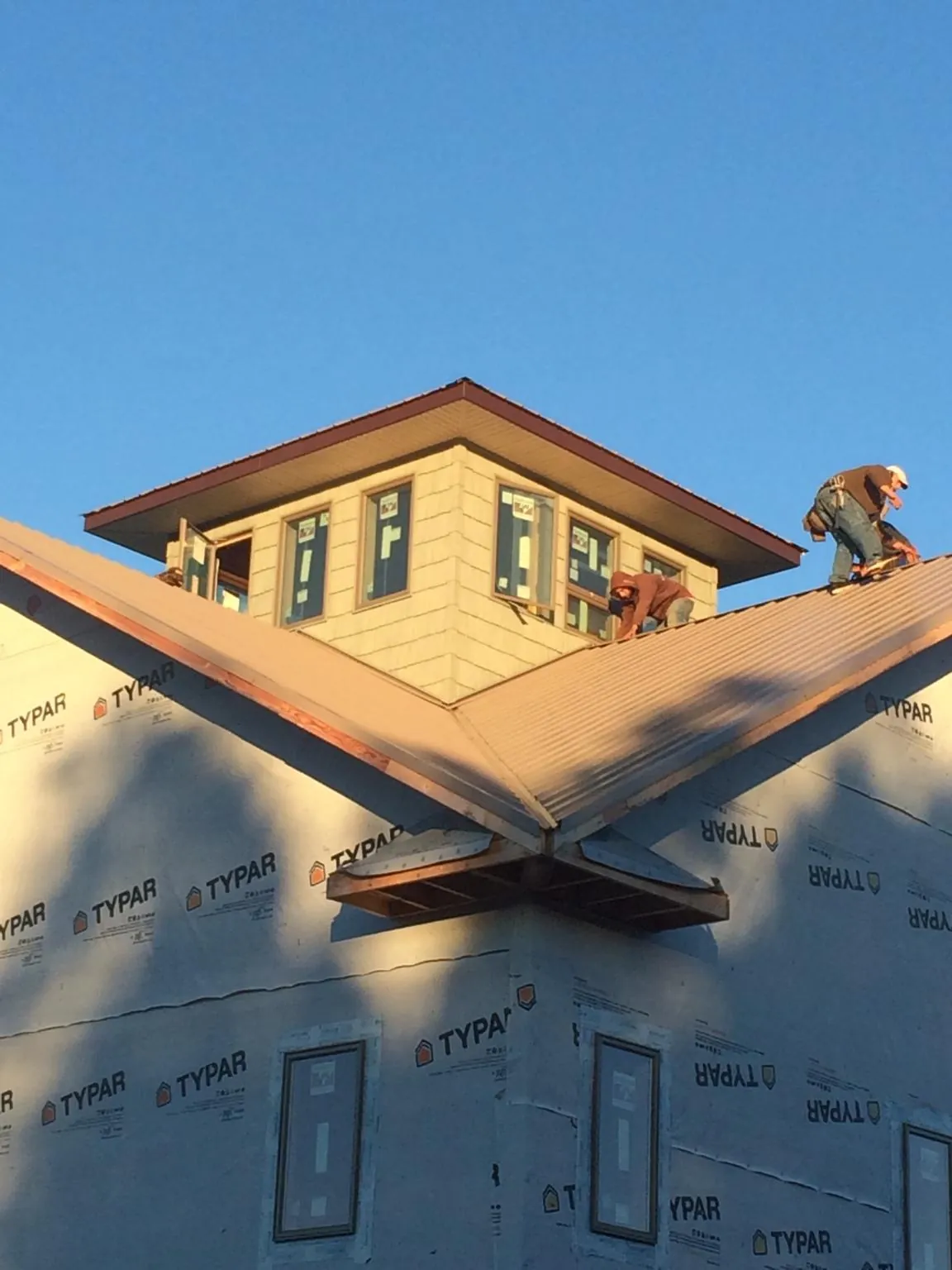 Roofers working around a rooftop cupola on a new metal roof at sunset — Roof Waterproofing in Texarkana by Roofing Brothers